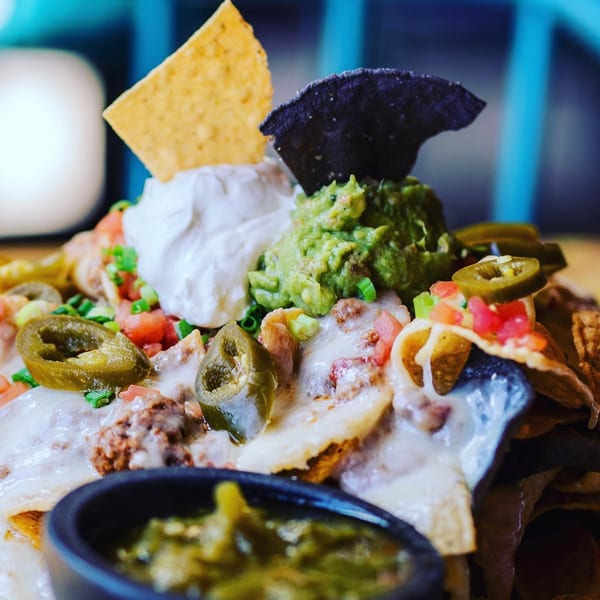 Close-up of Gazpacho Restaurant's loaded nachos with cheese, guacamole, sour cream, jalapeños, and salsa.