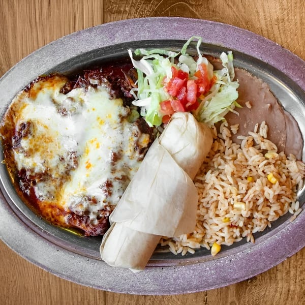 A Mexican combination plate with a cheesy enchilada, burrito, rice, refried beans, and salad.