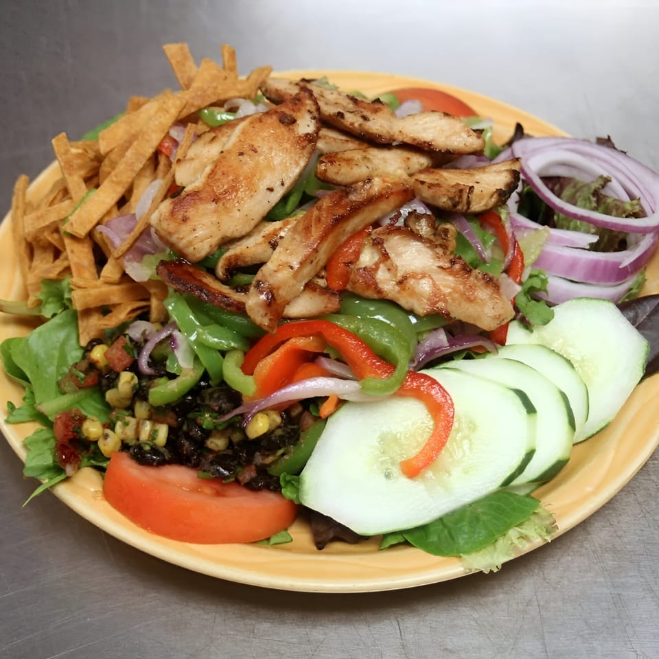 Grilled chicken salad with tortilla strips, bell peppers, red onions, cucumbers, and black bean corn salsa.